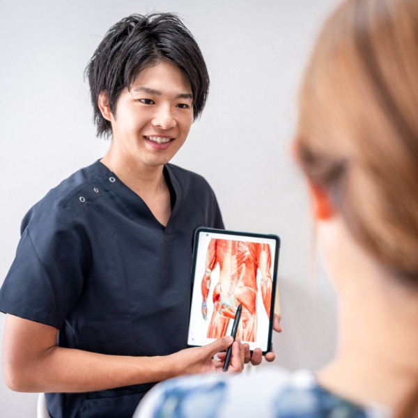 タブレットの図を見せながら、来院者に身体の状態を説明する院長